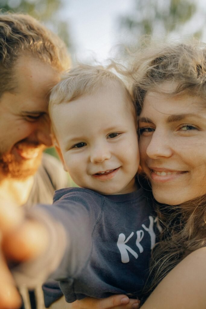 pexels-photo-4452215-4452215 Close-up of a happy family with a smiling child enjoying outdoor time together.